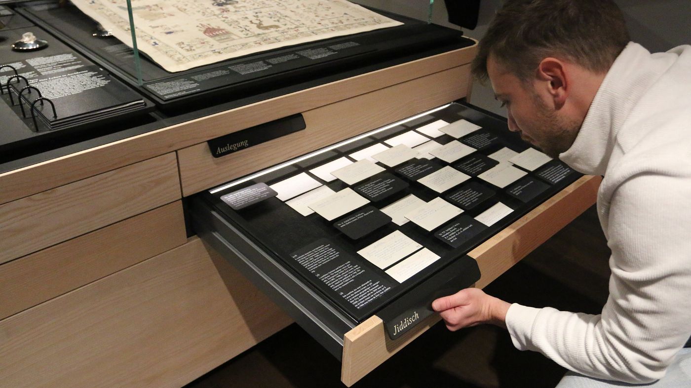 Ein Mann betrachtet Schubladen mit Karten voller handgeschriebener Notizen in einer Ausstellung.