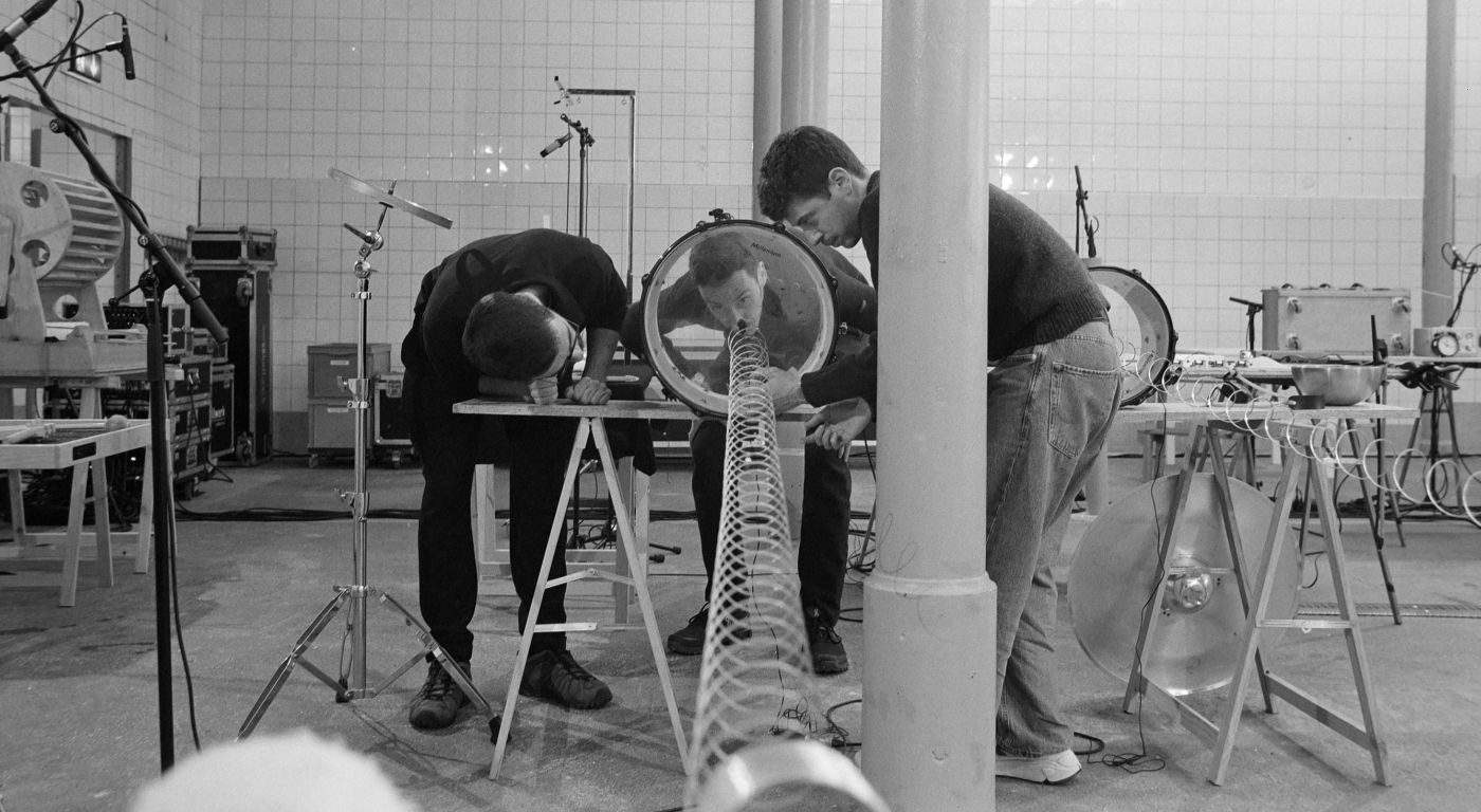 Drei Personen beugen sich über einen Tisch mit einem langen, spiralförmigen Instrument