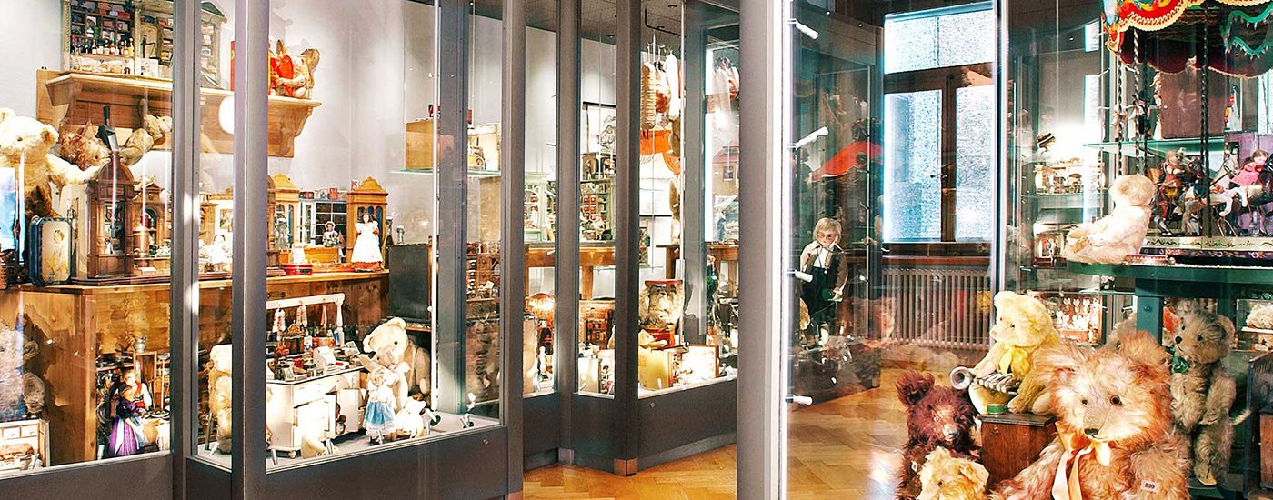 Various toys and teddy bears in illuminated museum showcases