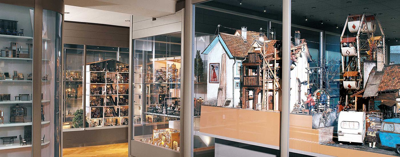 A miniature village with buildings, a Ferris wheel, and display case toys.