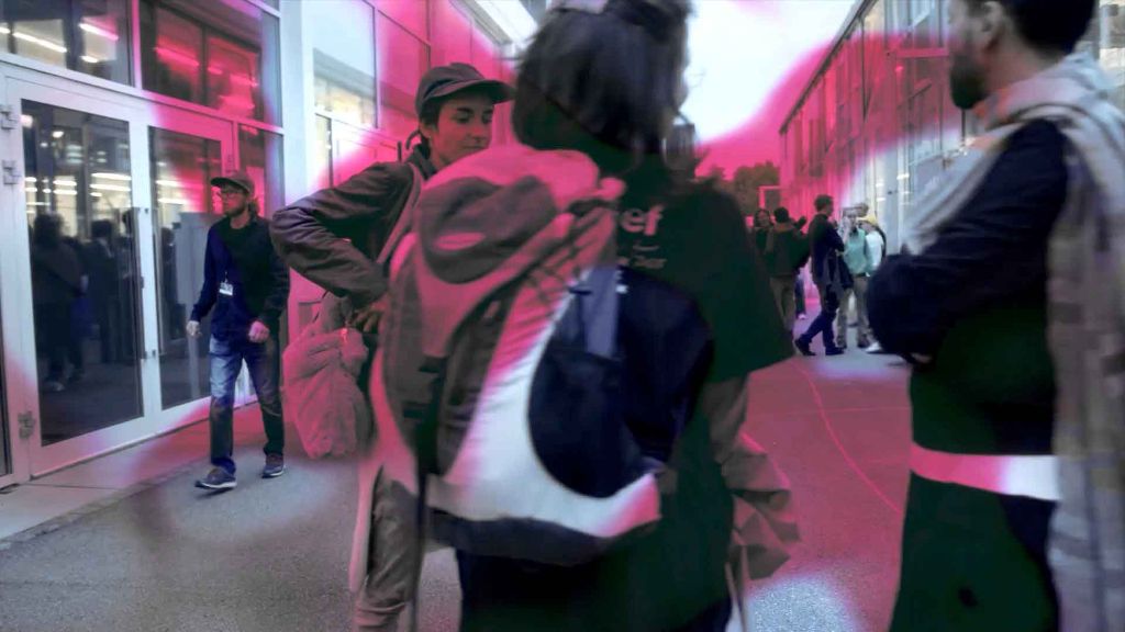 Menschen stehen in einer mit neonrotem Licht beleuchteten urbanen Szene im Freien
