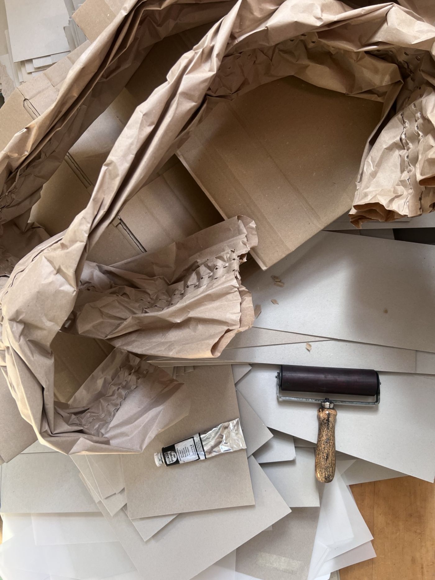 Ein Stapel Kartons und Papierbündel lehnt an einer Hauswand neben Briefkästen auf dem Bürgersteig