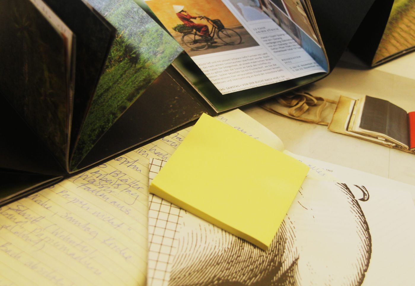 Zines mit bunten Bildern und handgeschriebenen Notizen liegen auf einem Tisch verstreut.