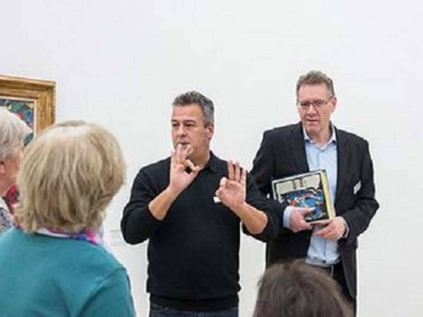 Un interprète en langue des signes explique à un groupe de personnes dans un espace d'exposition lumineux