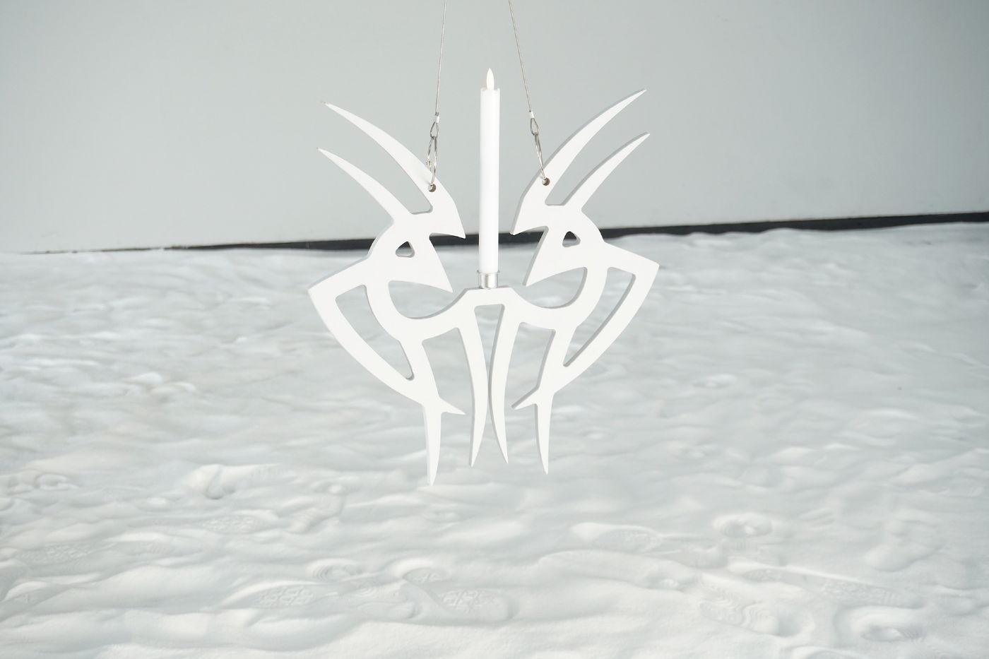 Eine abstrakte weisse Skulptur hängt vor einem Hintergrund, der wie frischer Schnee aussieht.
