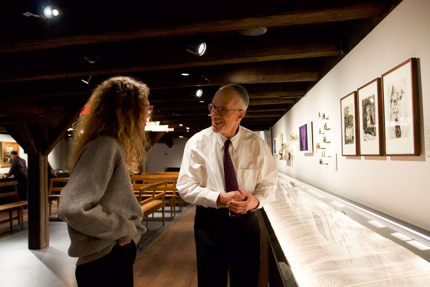 Zwei Personen stehen in einer Ausstellung und unterhalten sich lächelnd.