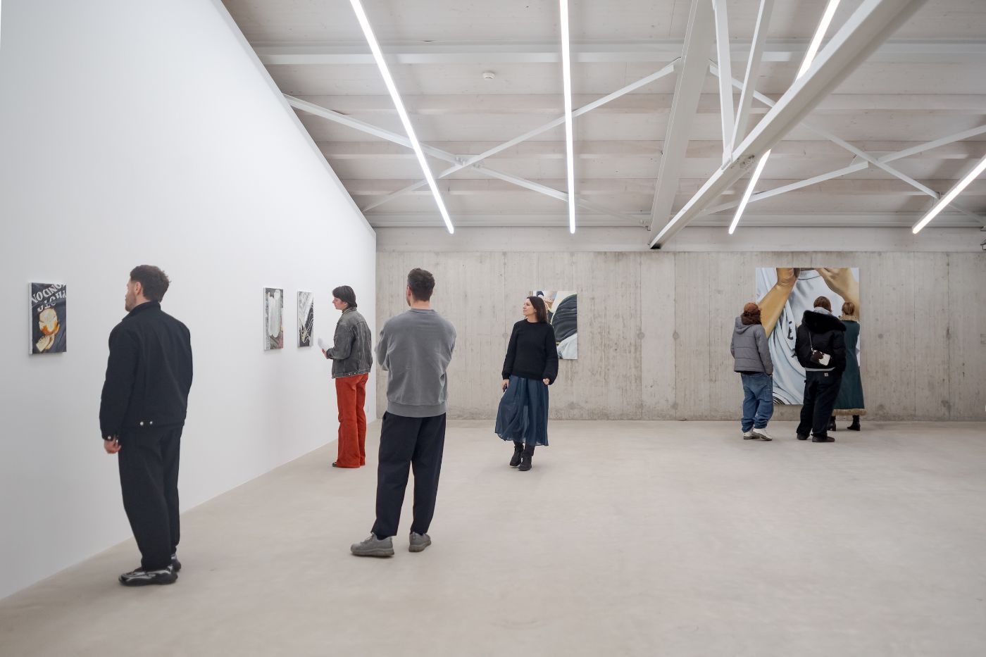 Sechs Personen betrachten Gemälde in einer hellen, minimalistischen Galerie mit Betonwänden
