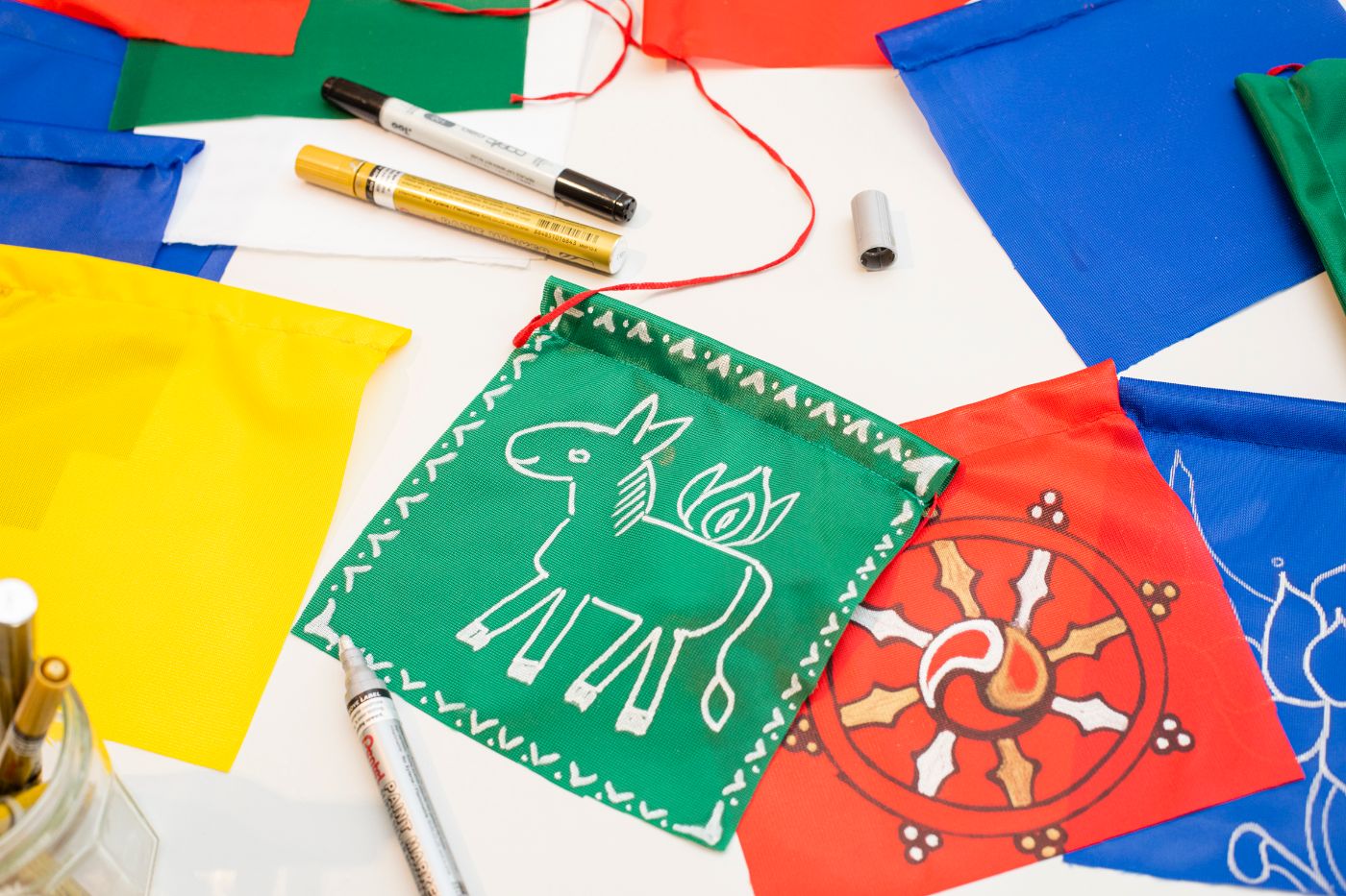 Auf einem Tisch liegen leere farbige Blätter und bedruckte Blätter, dazu Stifte.