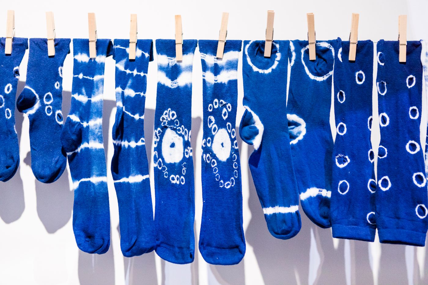 Blaue Socken mit weissen Mustern hängen mit Wäscheklammern an einer Leine.