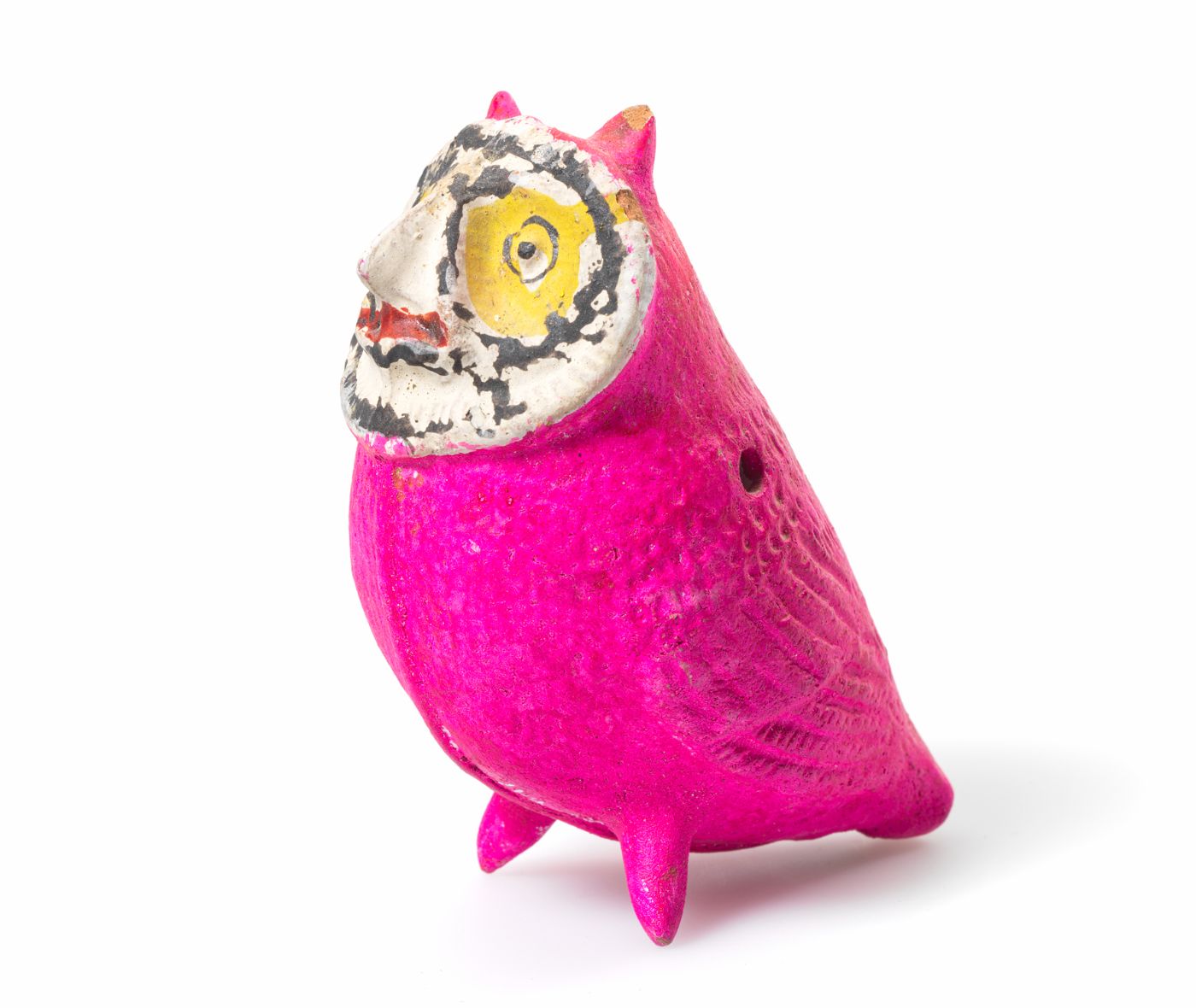 Figur einer Eule mit einem kleinen Loch im rechten Flügel. Die Eule hat einen pinken Körper und ein weiss-schwarz-gelb-rotes Gesicht.