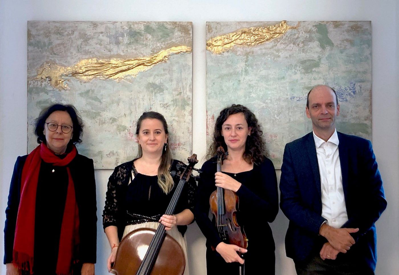 Vier Personen stehen vor zwei abstrakten Gemälden, zwei halten Musikinstrumente