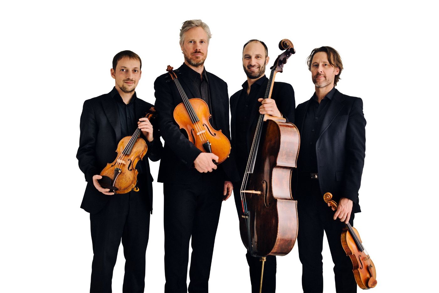 Vier Musiker in schwarzen Anzügen halten Streichinstrumente und blicken direkt in die Kamera