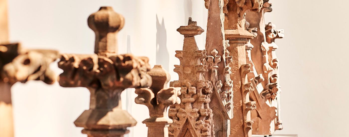 Verzierte mittelalterliche Skulpturen aus Stein stehen in einer Ausstellung aufrecht nebeneinander