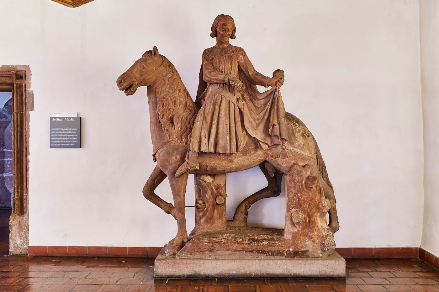 Eine Statue zeigt einen Reiter mit einem Mantel, der auf einem grossen Pferd sitzt.