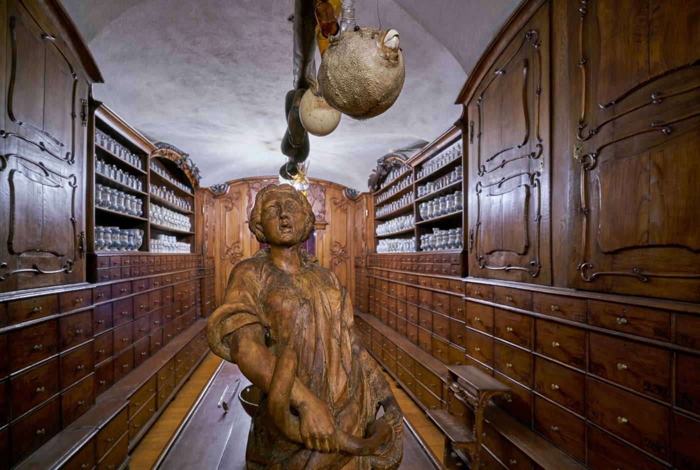 Hofapotheke aus Holz, Im Hintergrund Fayencen und Präparierte Tiere (Kugelfisch, Schlange)