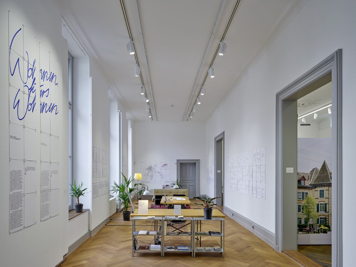 Ein heller Ausstellungsraum mit Pflanzen und Infotafeln an den Wänden