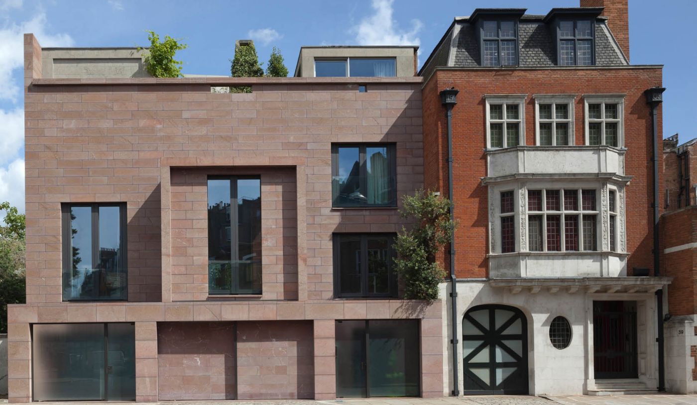 Ein modernes Backsteingebäude mit grossen Fenstern steht neben einem älteren Gebäude mit Erkerfenstern