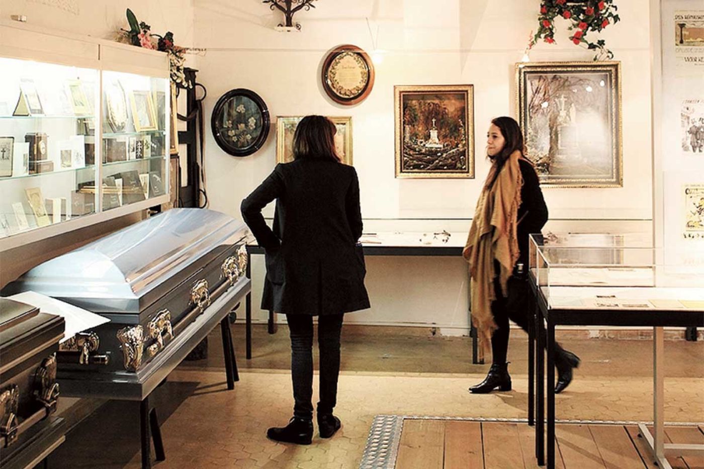 Zwei Personen betrachten Särge und historische Dokumente in einer Ausstellung