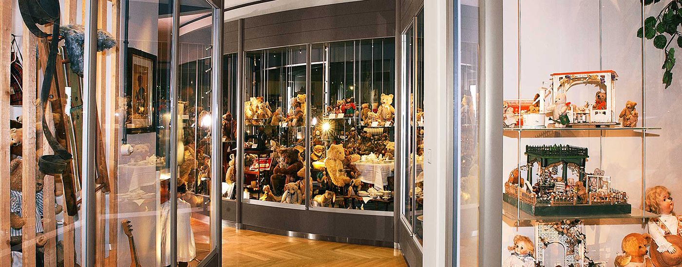 Teddy bears and dolls displayed in a stylish cabinet with warm lighting