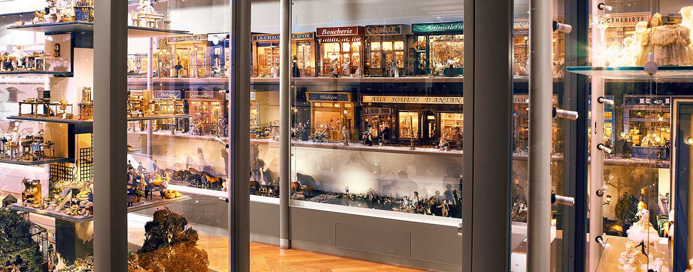 Display cases with detailed miniature houses and shops, surrounded by glass