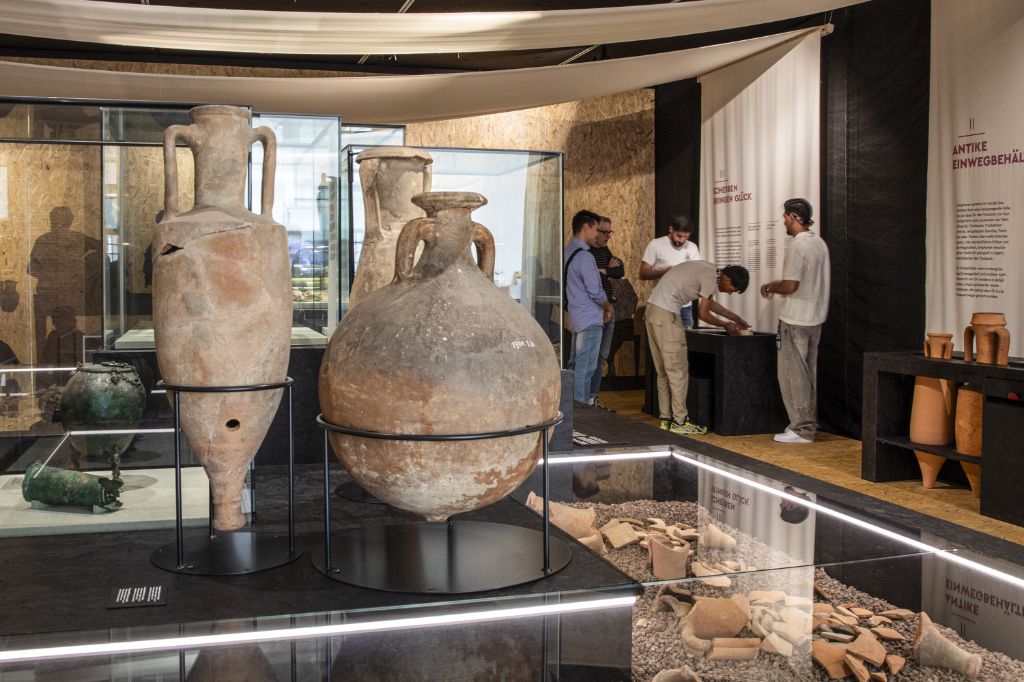 Visitors gaze at large clay amphorae and broken pottery pieces on display