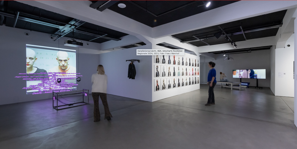 In einer Galerie stehen Besucher vor Projektionen und Porträts an den Wänden
