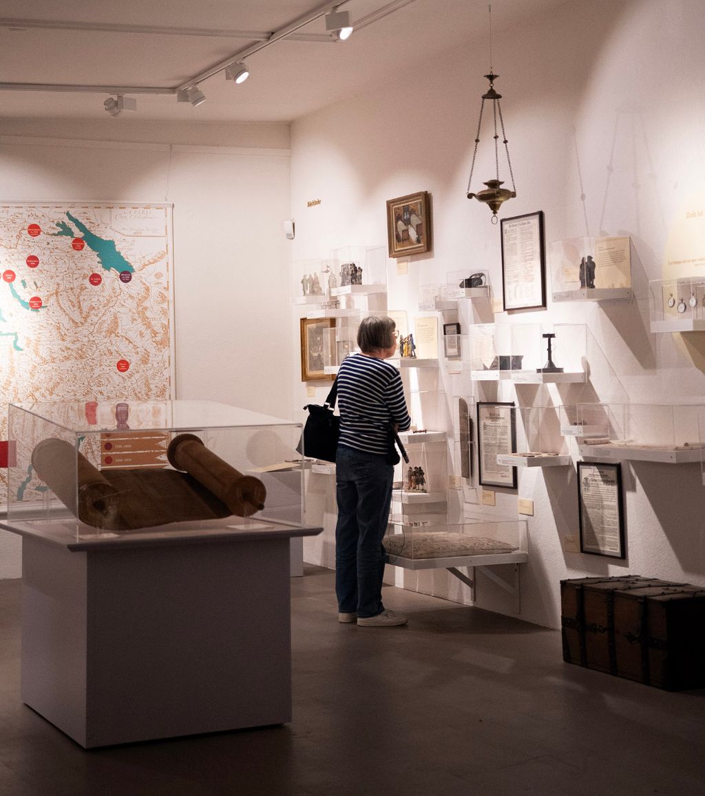Une femme examine des expositions dans une salle de musée bien éclairée avec des artefacts anciens