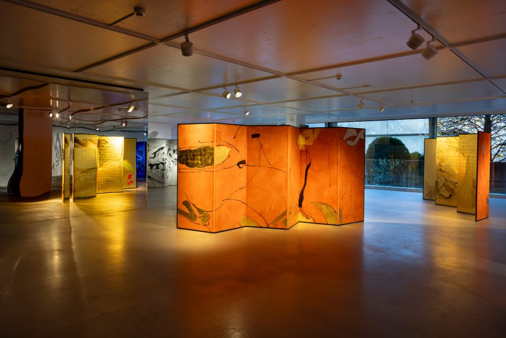 In a modern space, artistic screens with warm colors and abstract patterns are illuminated.