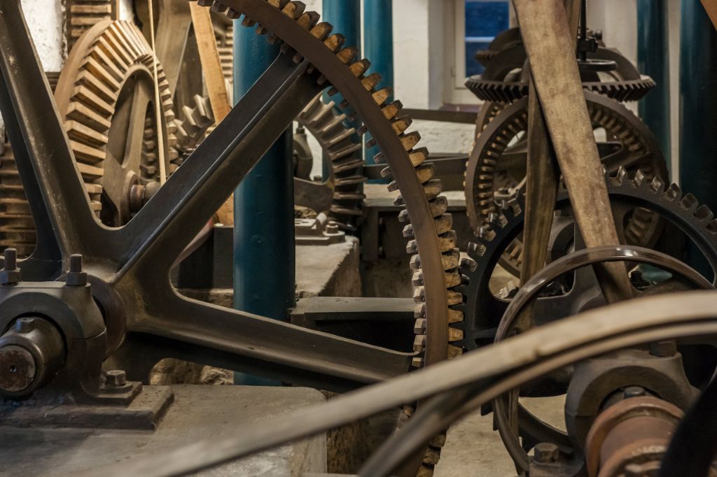 Des engrenages en bois et en métal s'emboîtent, montrant la complexité de la machinerie de moulin