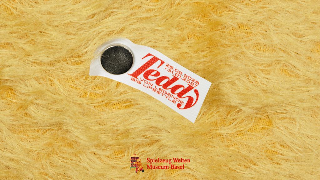 Ein gelbes Fell mit einem weissen Etikett, das in roter Schrift "Teddy, von Legende bis Lifestyle" zeigt