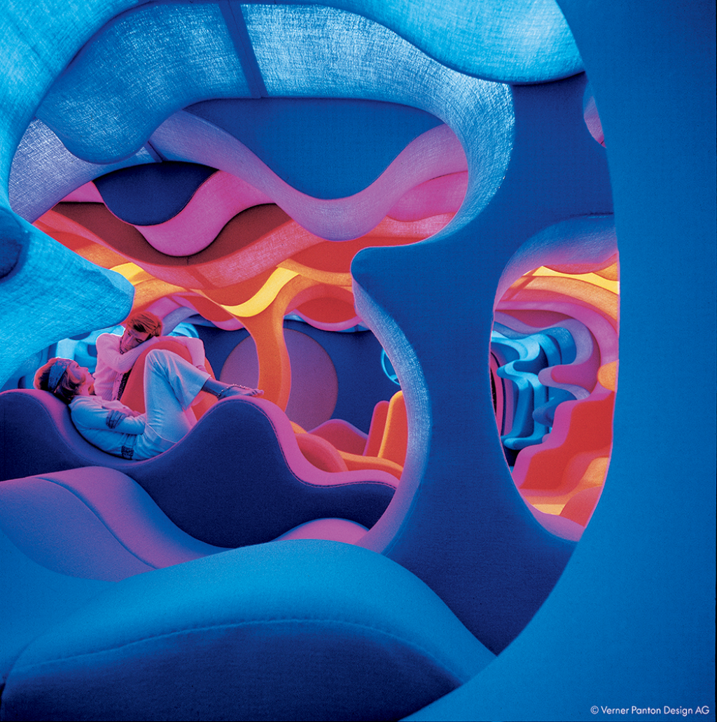 In a colorful, wave-shaped setting, two people sit relaxed on futuristic furniture